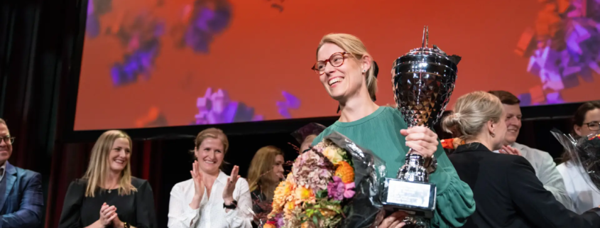 Marit Sandberg som vant forsker grand prix med en pokal og blomster i hendene