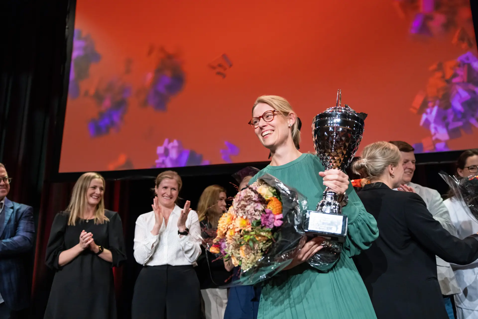 Marit Sandberg som vant forsker grand prix med en pokal og blomster i hendene